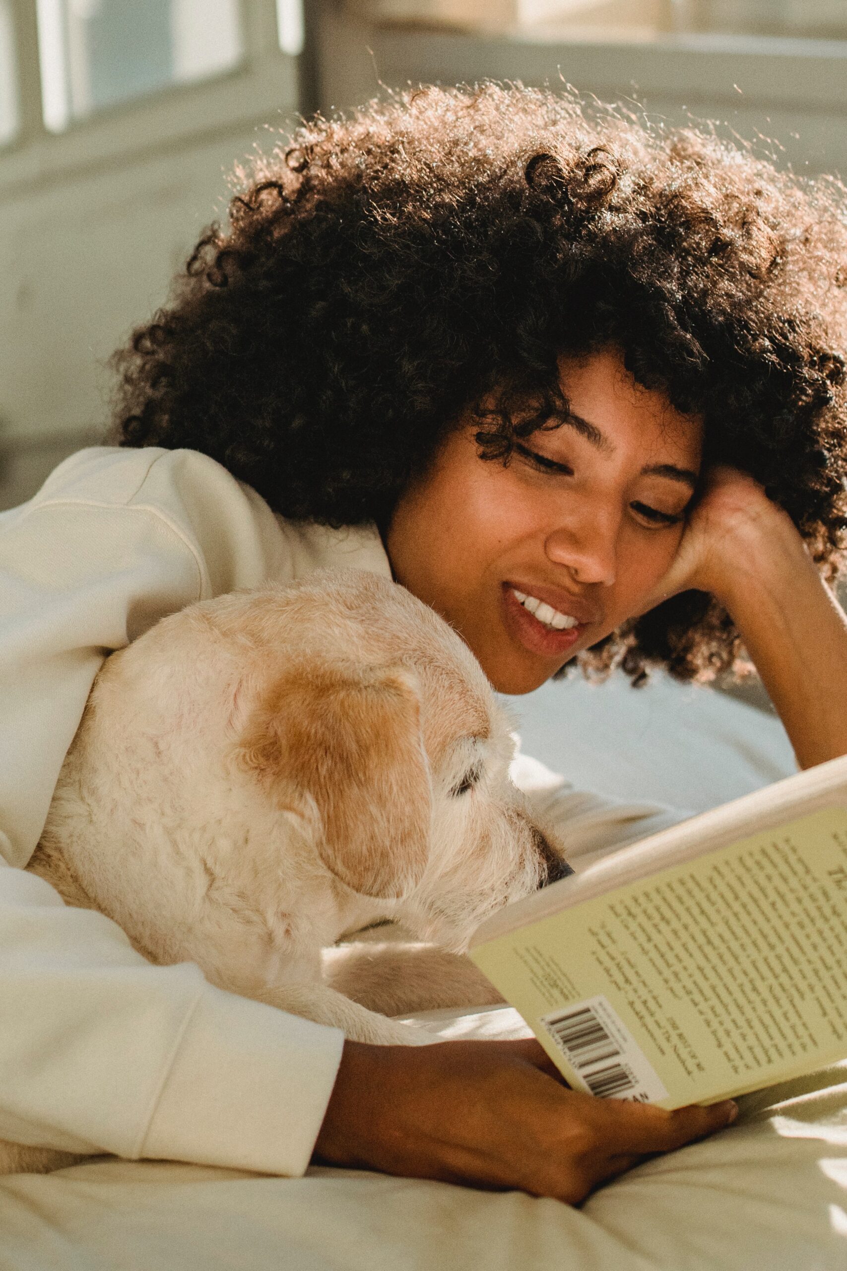 woman cuddling with a book and a dog around her arm